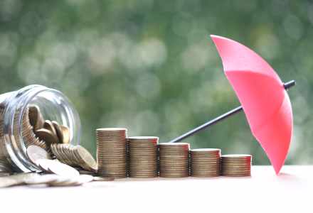 Protection, Stack of coins money in glass bottle with the umbrella on nature green background,Finance insurance and Safe investment concept